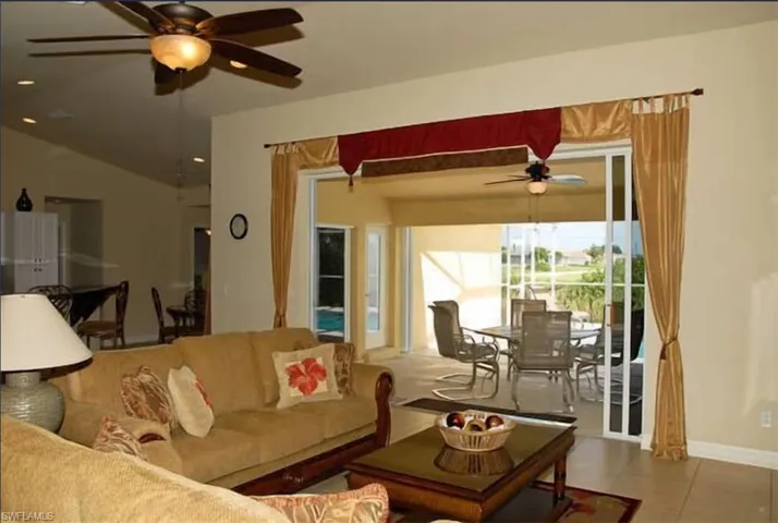 Living room featuring baseboards, tile patterned flooring, and a ceiling fan