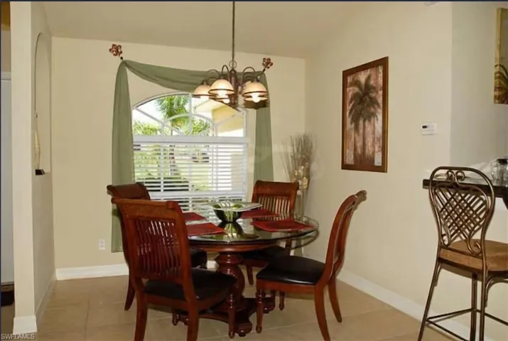 Tiled dining room with baseboards and a chandelier
