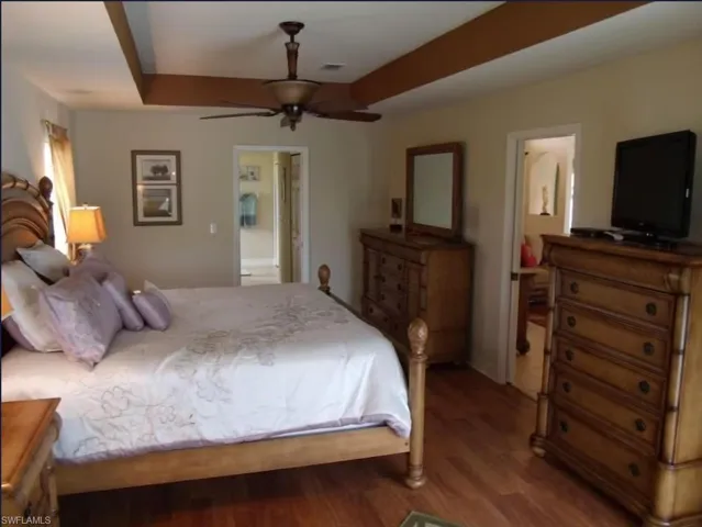 Bedroom with a tray ceiling, visible vents, and wood finished floors
