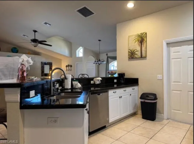 Kitchen with a sink, visible vents, dark countertops, and dishwasher