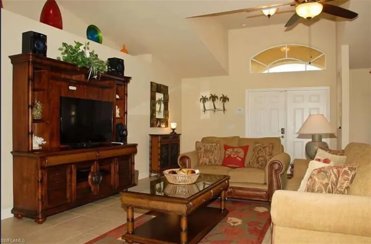 Tiled living area featuring a ceiling fan and vaulted ceiling