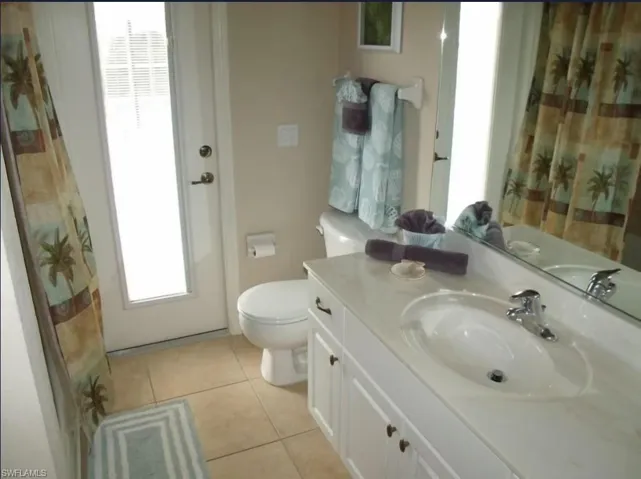 Full bathroom with a shower with curtain, tile patterned floors, vanity, and toilet