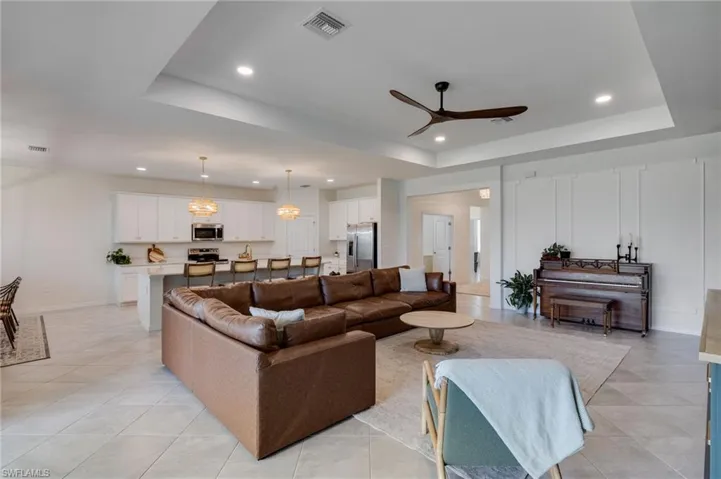 Open-concept living space featuring a tray ceiling with recessed lighting and a modern ceiling fan