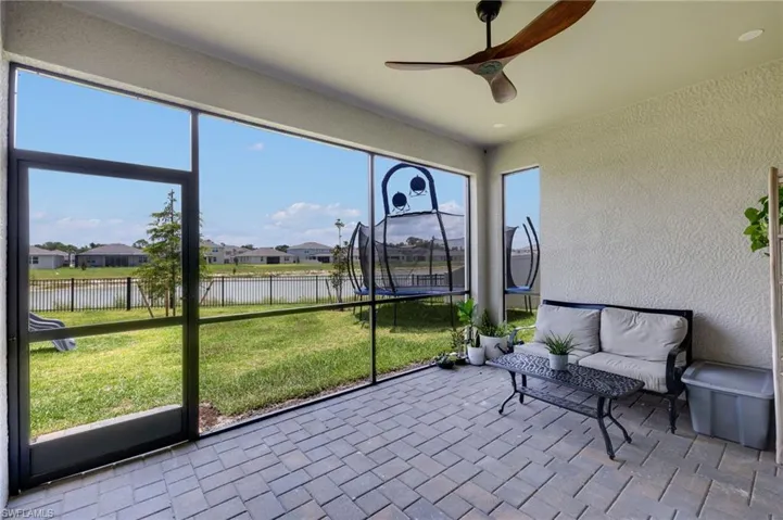 Spacious screened patio featuring paver flooring, a ceiling fan, and recessed lighting