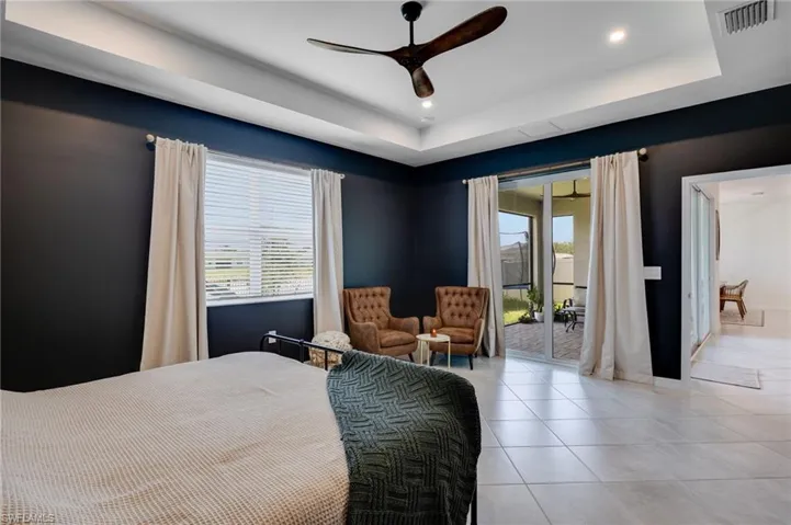 Recessed lighting illuminates a tray ceiling and a modern ceiling fan
