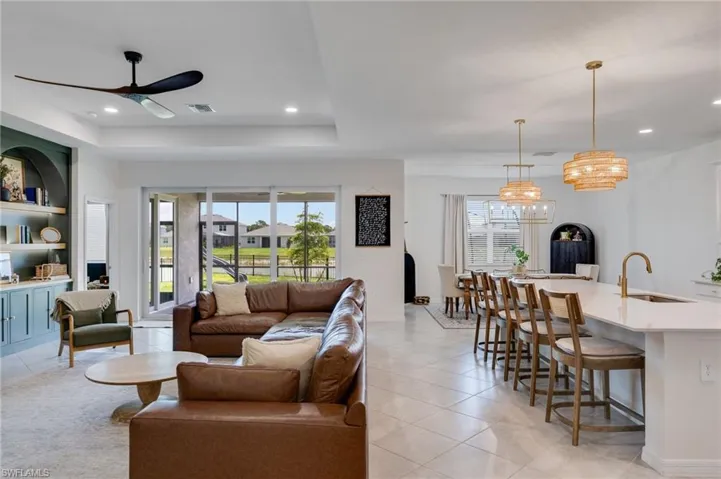 Open-concept living area featuring large format tile flooring, a contemporary ceiling fan, and built-in shelving with lower cabinetry