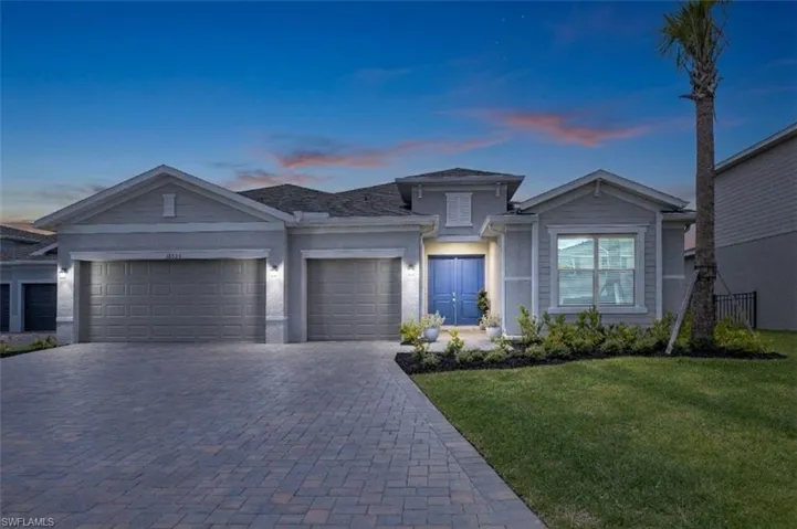 Contemporary-style residence featuring a two-car garage, paver driveway, and a prominent blue double-door entry