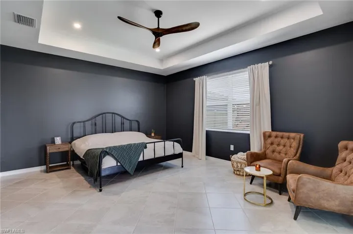 Spacious room featuring a tray ceiling with recessed lighting and a wood-finish ceiling fan