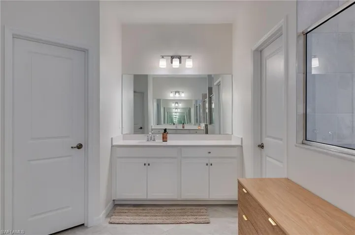 Dual-sink vanity with white cabinetry, light-toned countertop, and an expansive mirror