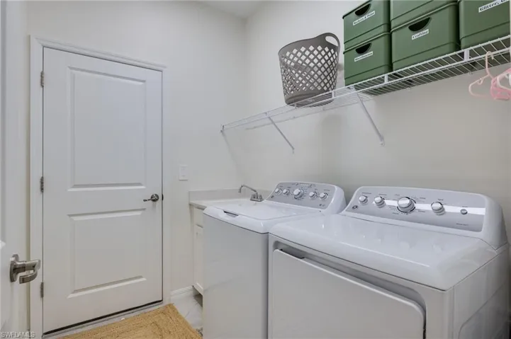 Dedicated laundry area featuring a white paneled door, wire shelving, and a built-in utility sink with a countertop