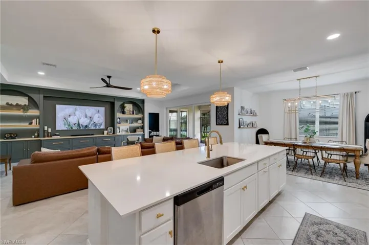 Expansive kitchen island featuring a stainless steel undermount sink, brass-finish faucet, and integrated dishwasher