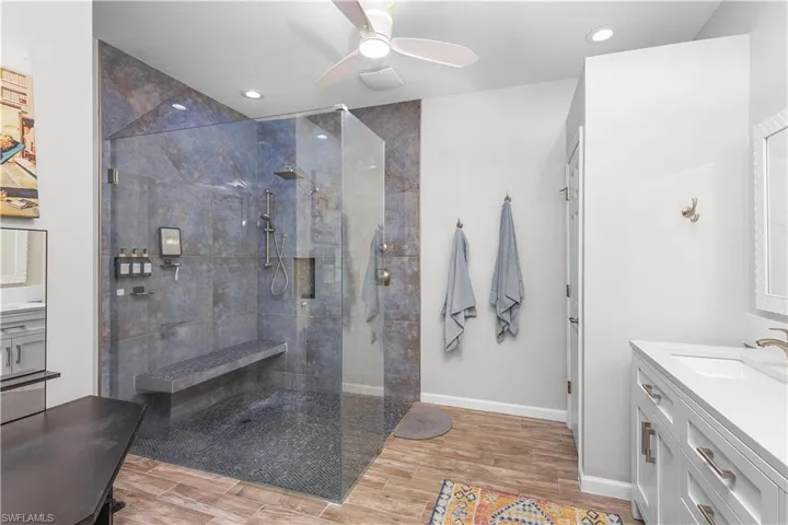 Bathroom with a tile shower, ceiling fan, vanity, and hardwood / wood-style flooring