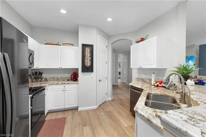 Kitchen featuring white cabinetry, sink, black appliances, and light hardwood / wood-style flooring