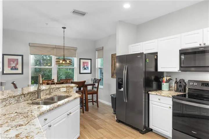 Kitchen with pendant lighting, sink, light hardwood / wood-style flooring, white cabinetry, and stainless steel appliances