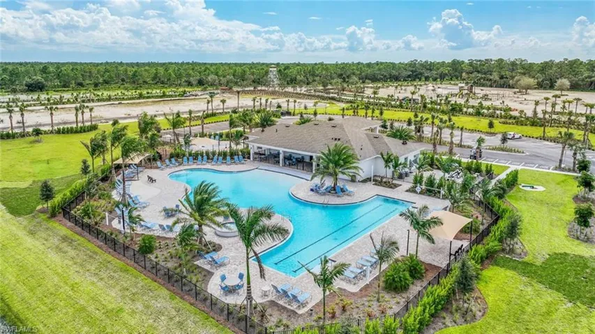 Outdoor pool area featuring a large swimming pool, lounge chairs, and surrounding palm trees