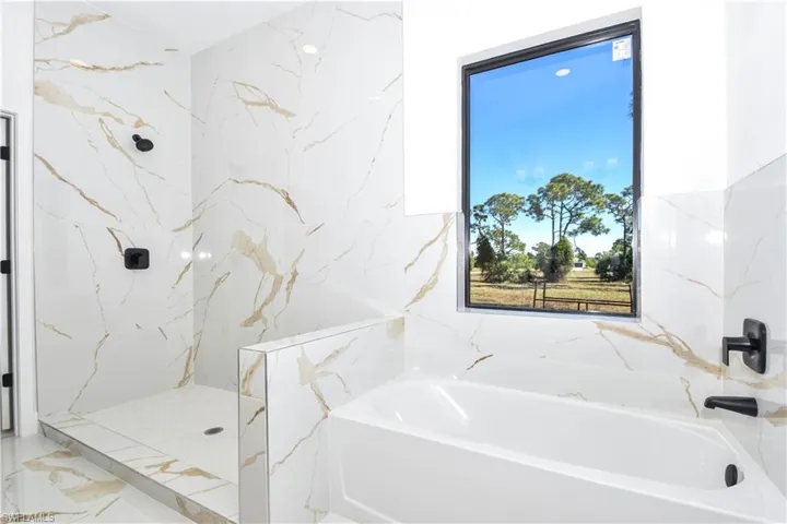 Primary Full bath featuring a bath, a marble style finish shower