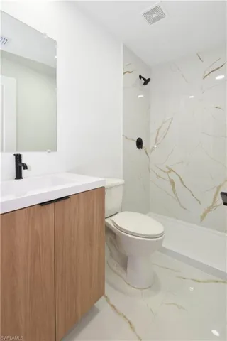 Bathroom with vanity, a marble style finish shower, and light marble finish flooring