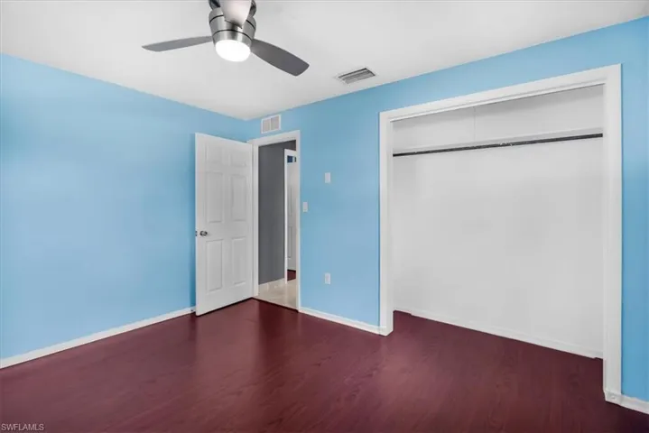 Wood-finish flooring, ceiling fan with integrated lighting, solid core door, and built-in closet with hanging rod