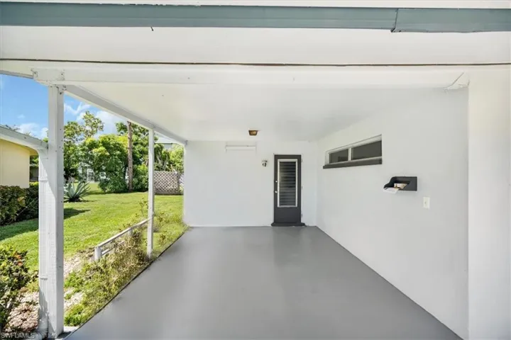Covered patio with a concrete floor, exterior door with louvered inserts, and a horizontal window