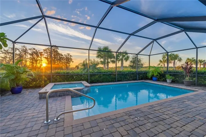 Pool at dusk with a lanai, an in ground hot tub, and a patio
