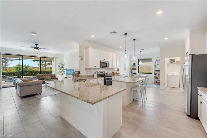 Kitchen featuring decorative light fixtures, stainless steel appliances, kitchen peninsula, and a wealth of natural light