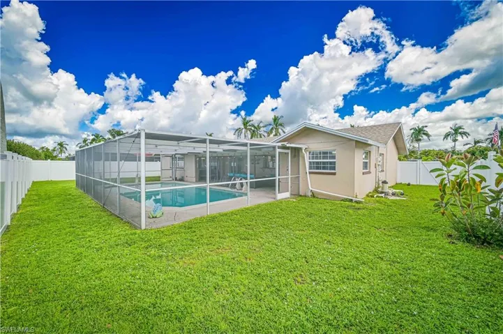 Rear view of property featuring glass enclosure, a fenced backyard, a sunroom, stucco siding, and a patio
