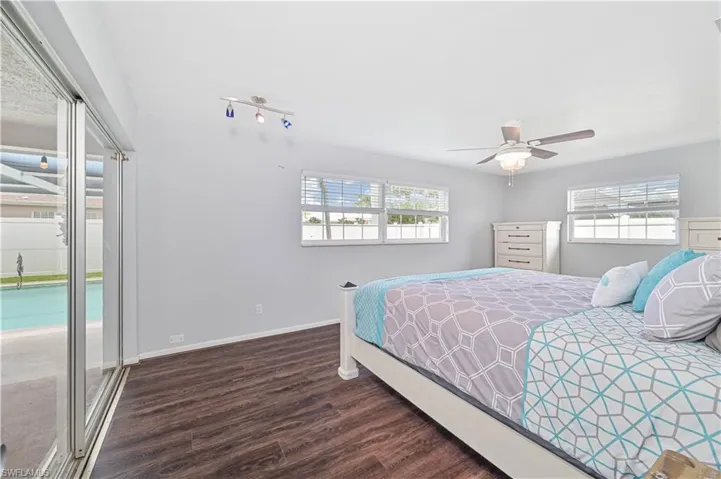 Bedroom featuring multiple windows, wood finished floors, access to exterior, and a ceiling fan