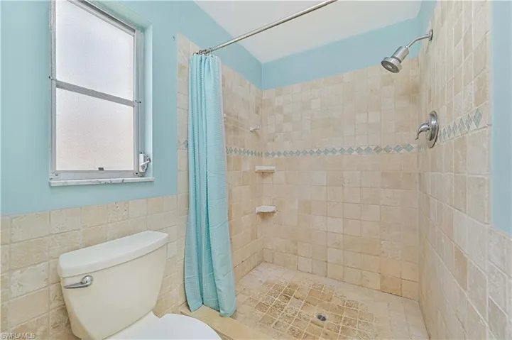 Full bath featuring tile walls, a shower stall, and a wainscoted wall