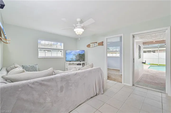 Tiled living room with a ceiling fan and baseboards