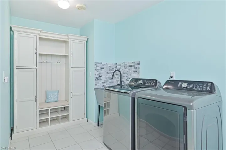 Laundry area featuring light tile patterned floors and washer and clothes dryer