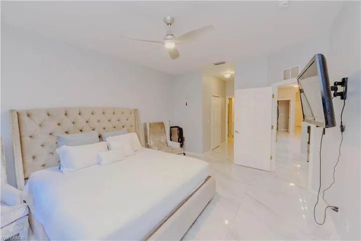 Bedroom featuring a ceiling fan, a closet, and light marble finish floors