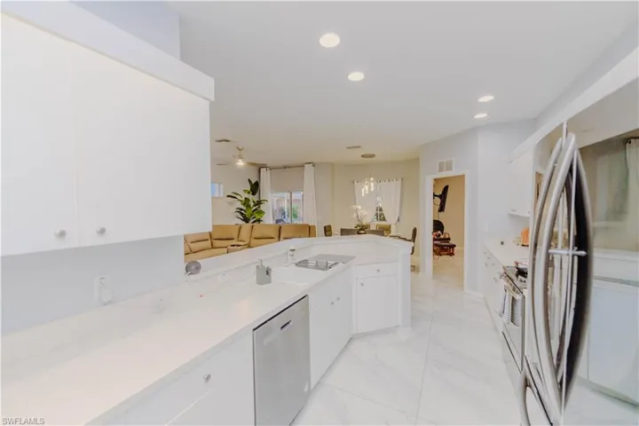 Kitchen featuring appliances with stainless steel finishes, white cabinets, recessed lighting, decorative light fixtures, and a peninsula