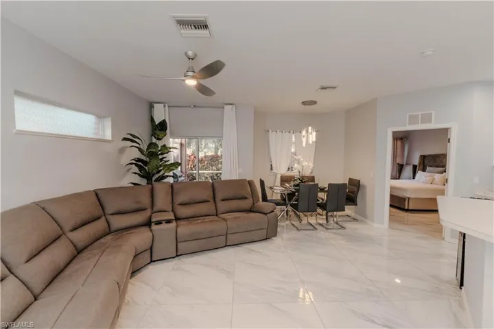 Living room with a ceiling fan and light marble finish flooring
