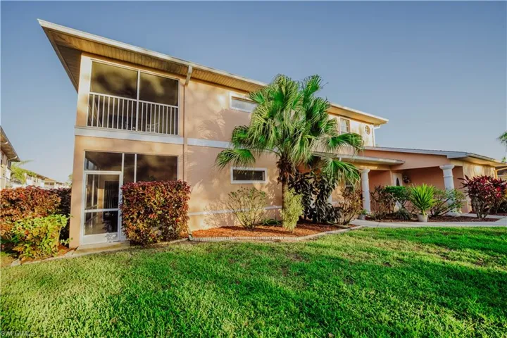 Rear view of house with a sunroom, a yard, stucco siding, and a balcony