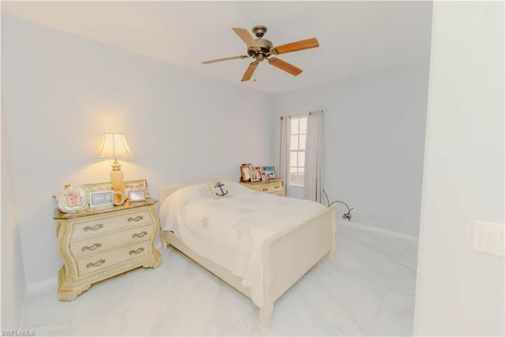 Bedroom with ceiling fan and marble look tile flooring
