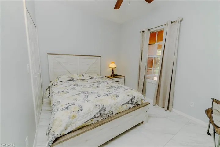 Bedroom featuring a ceiling fan and light marble finish floors