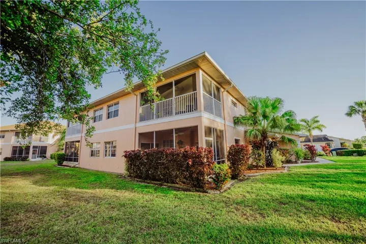 Back of house featuring a sunroom, a lawn, stucco siding, and a balcony