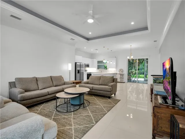 Living Room with large tile flooring, tray-ceiling and ceiling fan with lighting