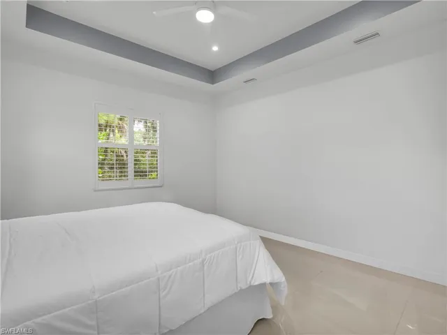 Primary Bedroom Primary Bedroom with large tile flooring, ceiling fan, and tray ceiling