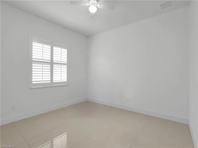 Guest Bedroom #3 with large tile flooring and ceiling fan with lighting