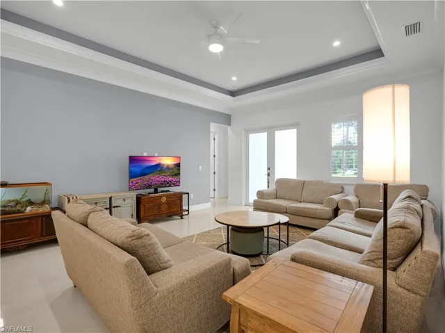Living Room with large tile flooring, tray-ceiling and ceiling fan with lighting
