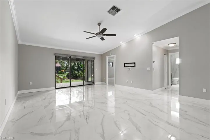 Empty room featuring lofted ceiling, ornamental molding, and a ceiling fan
