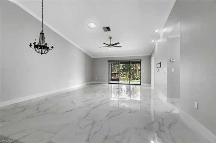 Empty room with crown molding, ceiling fan, light marble finish floors, and suspended lighting