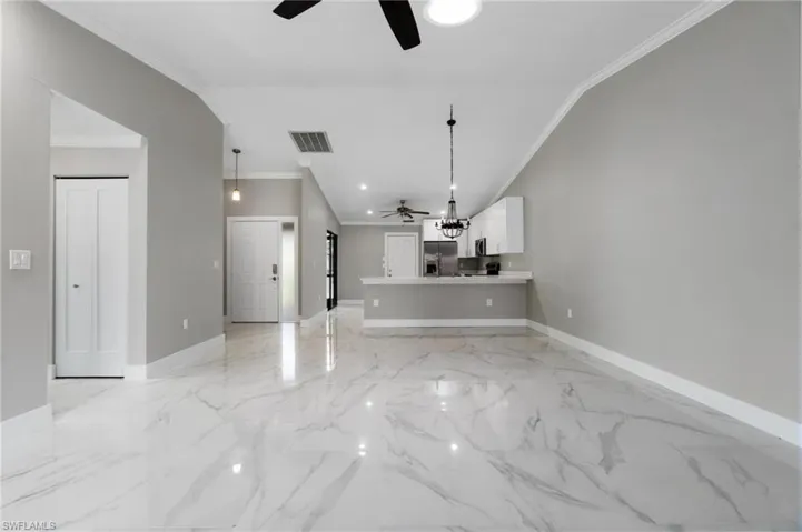 Unfurnished living room featuring ceiling fan and crown molding