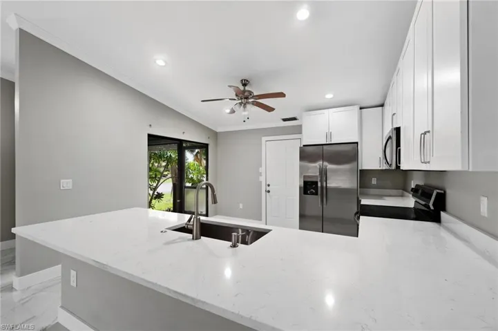 Kitchen featuring a peninsula, stainless steel appliances, white cabinetry, recessed lighting, and ceiling fan