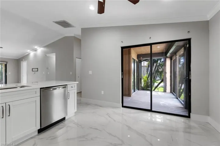 Kitchen featuring ornamental molding, ceiling fan, dishwasher, white cabinets, and light marble finish flooring