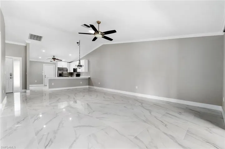 Unfurnished living room featuring crown molding, ceiling fan, suspended lighting, and lofted ceiling