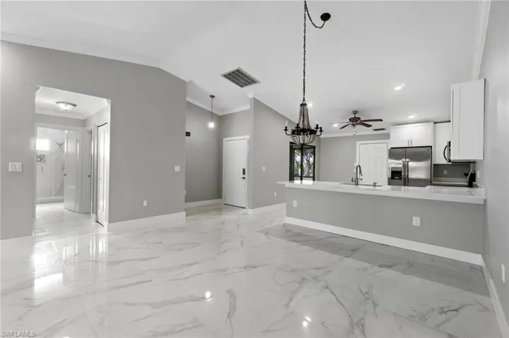 Unfurnished living room featuring crown molding, lofted ceiling, a ceiling fan, and light marble finish flooring