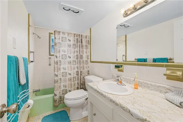 Full bathroom featuring tile walls, backsplash, shower / bath combo with shower curtain, vanity, and toilet