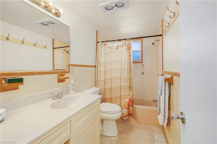 Full bathroom featuring shower / bath combination with curtain, tile walls, vanity, and toilet